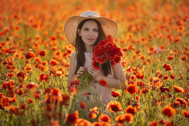 νεαρό κορίτσι σε ένα χωράφι με κόκκινες παπαρούνες - Φωτογραφία, εικόνα