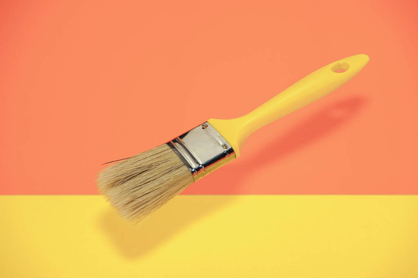 Nova escova de pintura em um fundo laranja e amarelo coral
. - Foto, Imagem
