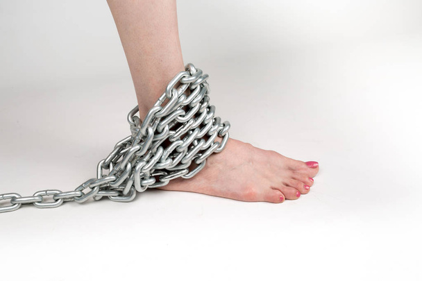thick metal chain around the woman foot - Foto, Imagen