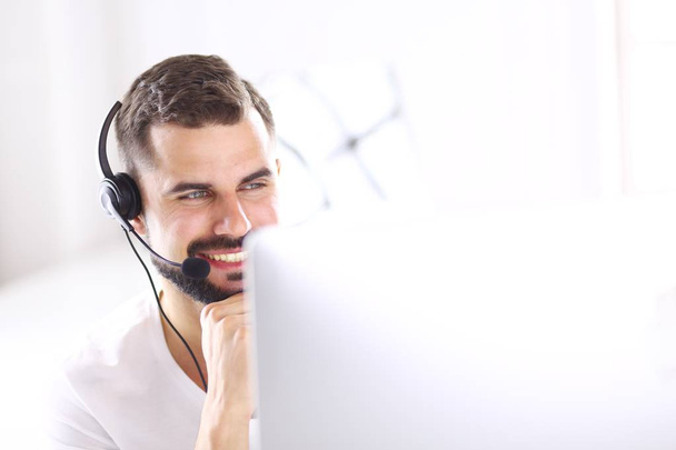 Portrait of a young man with a headset in front of a laptop computer - Foto, Bild