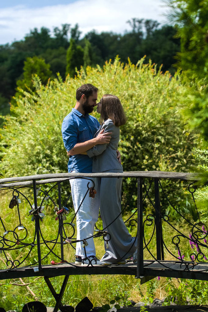 Jeune et élégant couple amoureux stand et joue le fou, amusant, embrasse dans le parc sur le pont parmi les verts d'été
. - Photo, image