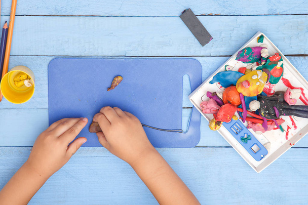 as mãos de crianças esculpem números de barro em uma mesa azul. o vie
 - Foto, Imagem