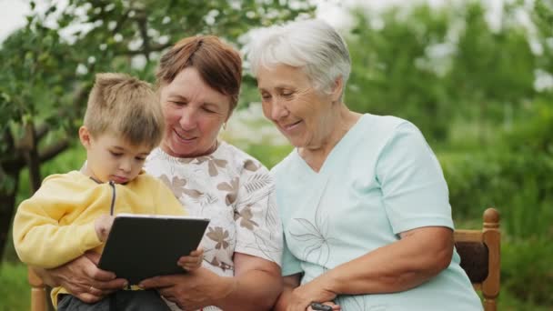 Großmütter schauen auf ein Tablet in den Händen eines Enkels - Filmmaterial, Video