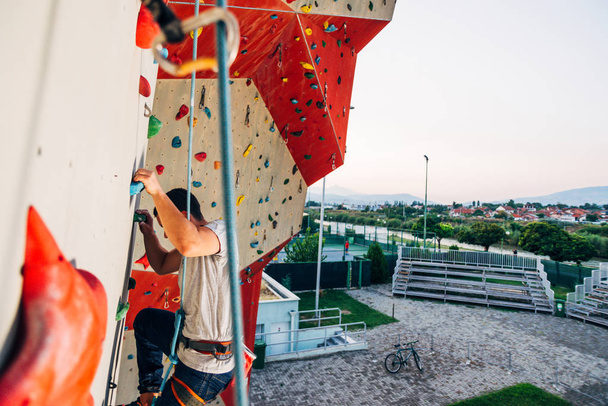 Jeune homme sportif grimpant sur le mur de montage pratique en plein air
 - Photo, image