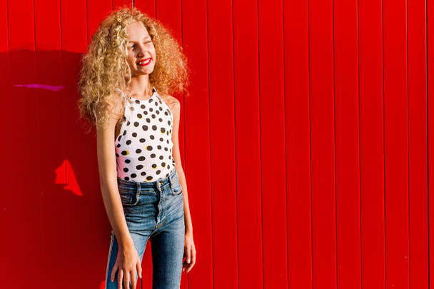 Девушка-подросток позирует на фоне красной стены
 - Фото, изображение
