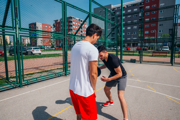 Dos jugadores de baloncesto callejeros jugando uno contra uno mucho de cerca la acción y la guardia de la pelota
. - Foto, Imagen