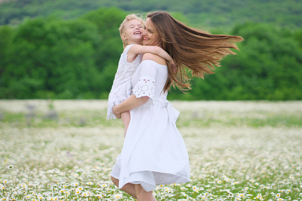 Ευτυχισμένη μητέρα και κόρη σε χαμομήλι λιβάδι - Φωτογραφία, εικόνα