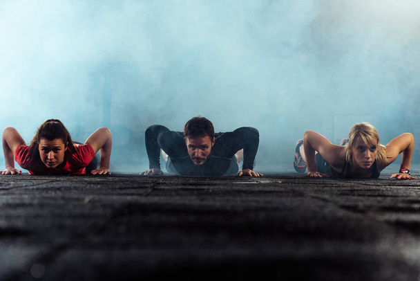 Три людини роблять пульсації на тренуваннях у спортзалі
 - Фото, зображення