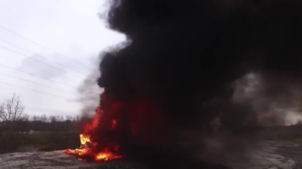 Ogromny płomień palenia ognia w pełni spala brudny stary samochód w lewo na opuszczonej drodze. - Materiał filmowy, wideo