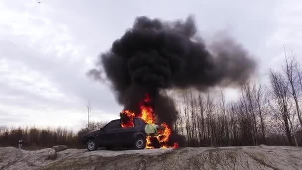 Velké kouřící plameny ohně úplně spálí staré špinavé auto na opuštěné silnici. - Záběry, video
