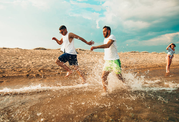 Мужчины бегают по пляжу в море
 - Фото, изображение