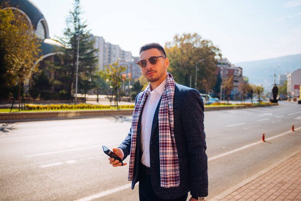 Joven hombre de negocios caminando por el bulevar con sus gafas de sol
 - Foto, imagen