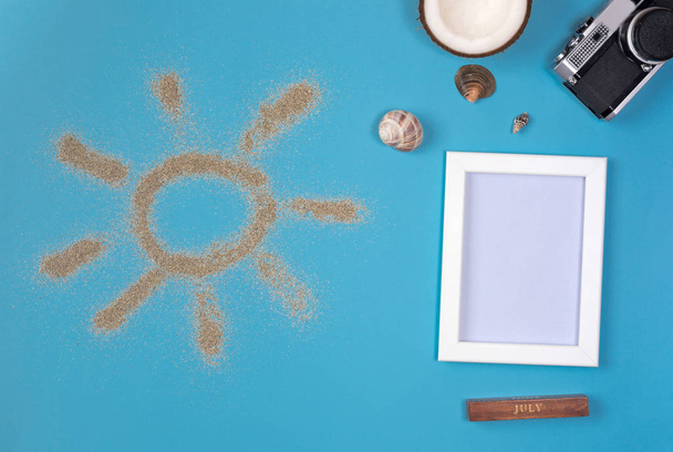 Photo frame and camera on blue background. Sun drawn by the sand on blue background. Top view. - Φωτογραφία, εικόνα