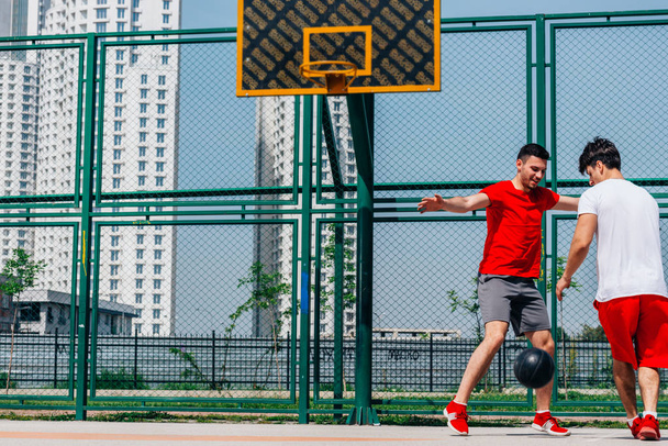 Basketbol maçı. Kırmızı giyen siyah bir top ile top oynamak, gr - Fotoğraf, Görsel