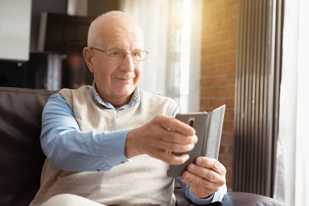 Smiling senior man using a smartphone - Zdjęcie, obraz