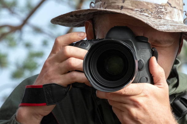 Traveler photographer in a hat looks into the camera lens. Lifestyle, photo story, natural photography. Travel and tourism. - Photo, Image