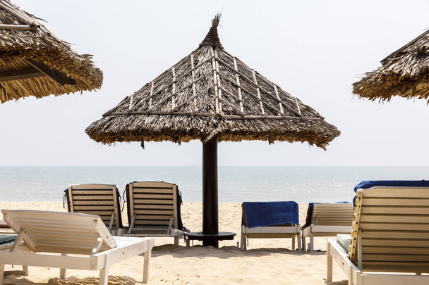 Cadeiras de convés e sombra na praia ensolarada
 - Foto, Imagem