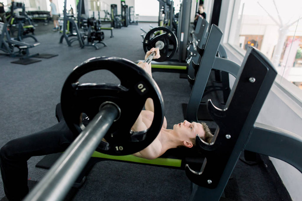 Man with barbell during bench press exercise in gym. Mature Man In Gym Exercising On The Bench Press - Fotó, kép