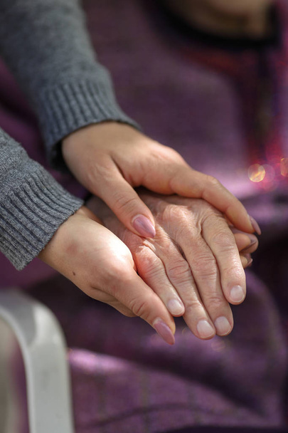 Genç bakıcı yaşlıların elini tutuyor. Yaşlı kavramı - Fotoğraf, Görsel