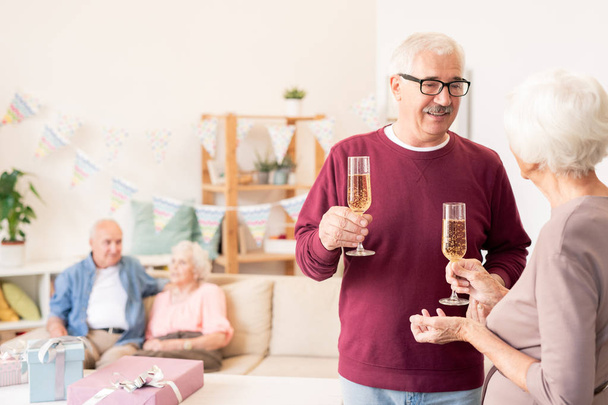 Vanhemmat puolisot paahtavat huilulla samppanjaa juhliessaan lomaa ystävien kanssa
 - Valokuva, kuva