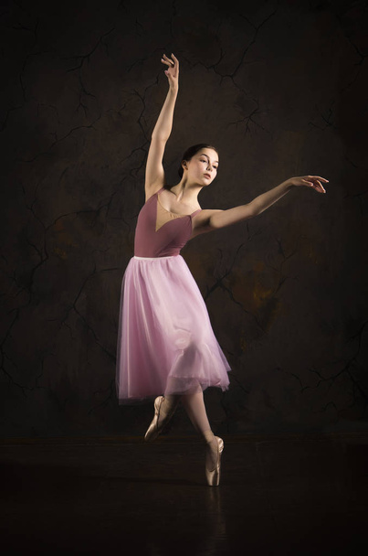 A slender girl in a pink skirt and beige top dancing ballet. - Foto, afbeelding