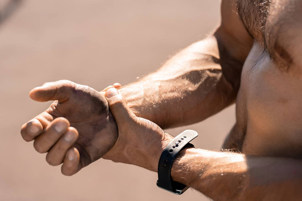 Contemporain jeune sportif torse nu avec smartwatch toucher son poignet blessé pendant l'entraînement
 - Photo, image