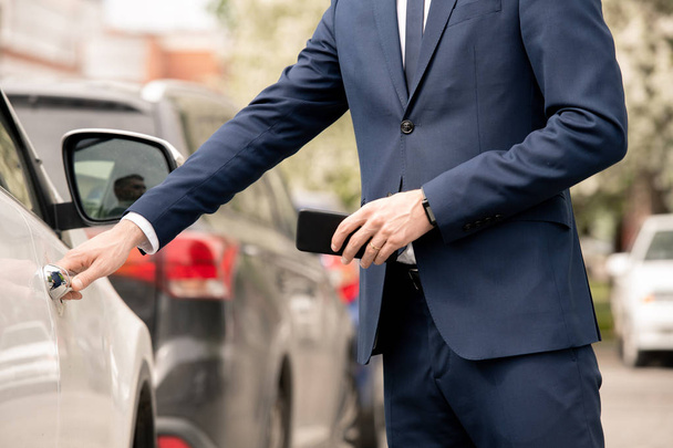 Jonge elegante zakenman in formalwear openings deur van auto of taxi cabine tijdens het gaan voor een ontmoeting met partners - Foto, afbeelding