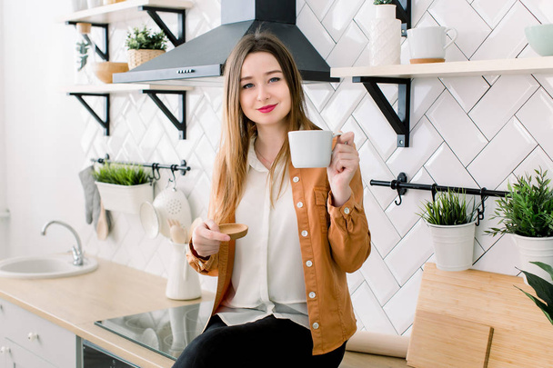 Portrait of Young adult brunette woman with morning coffee in the kitchen - Photo, Image
