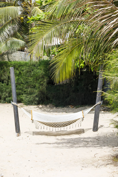 White hammock hangs on a sandy beach - Fotoğraf, Görsel