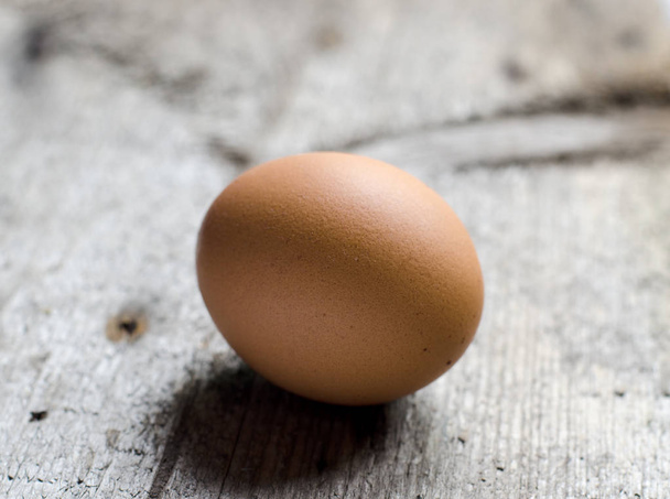 Chicken brown egg on a vintage rustic wooden board. - Photo, Image
