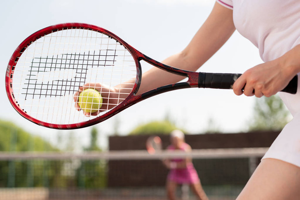 Joueuse de tennis tenant le ballon sur la raquette tout en allant le jeter à son compagnon de jeu
 - Photo, image