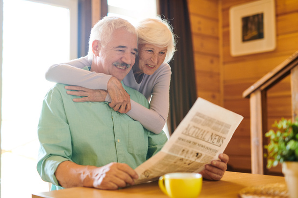 Χαρούμενο ζευγάρι ηλικιωμένων στο εξοχικό τους κοιτάζοντας τα τελευταία νέα το πρωί - Φωτογραφία, εικόνα