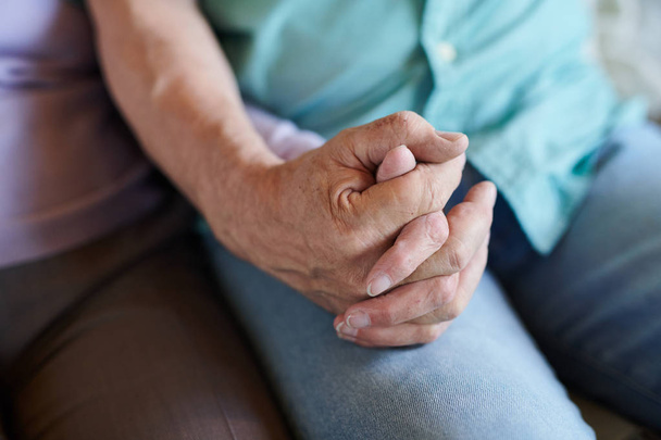 Starszy mężczyzna w niebieskie dżinsy trzyma rękę swojej żony, podczas gdy zarówno relaks w domu przed TV ustawić w czasie wolnym - Zdjęcie, obraz