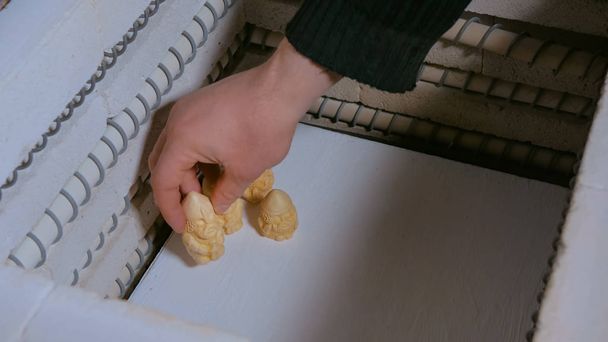 Поттер помещает керамические фигурки в керамическую печь
 - Фото, изображение