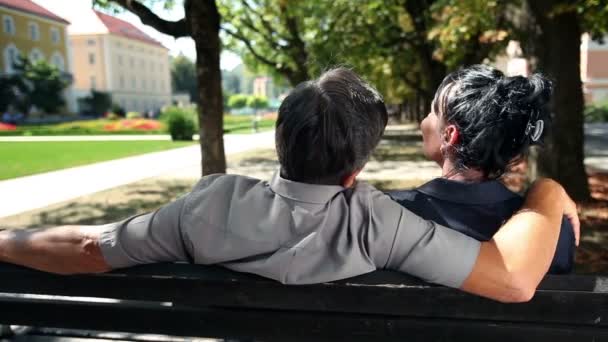 座っているカップル、カゼルタヴェッキアの公園のベンチに夏の日のショット - 映像、動画
