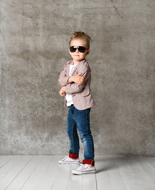 Image of cheerful excited little boy child standing isolated over concrete wall. - Foto, Imagen