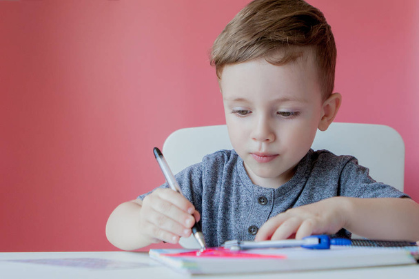 Portrait of cute kid boy at home making homework. Little concentrated child writing with colorful pencil, indoors. Elementary school and education. Kid learning writing letters and numbers - Zdjęcie, obraz