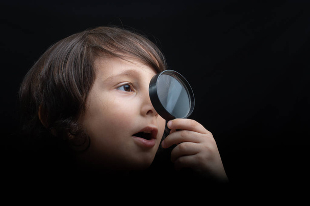 Portrét mladého chlapce, jak se dívá skrz zvětšovací sklo - Fotografie, Obrázek