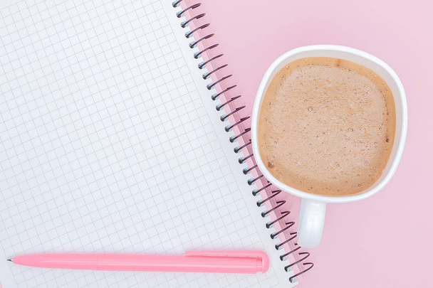 top view business background workspace with coffee, pen and blank notebook on pink background. image for education, desktop, copy space, work, workplace, beverage, mock up concept - Foto, immagini