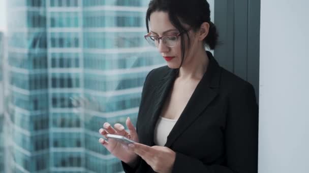 Portrait of a young businesswoman with a mobile phone in her hands. the girl is intently using a smartphone. - Footage, Video