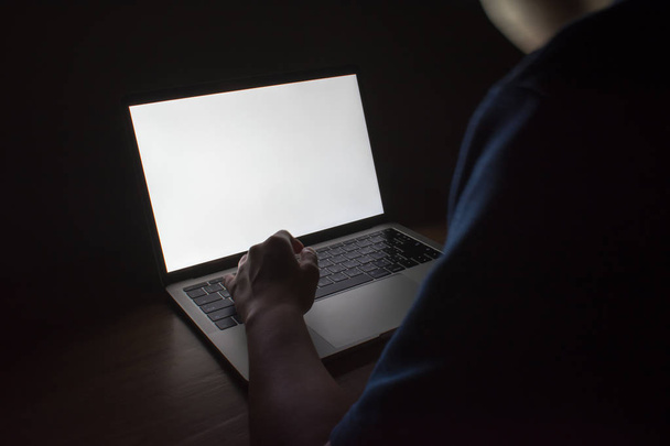 Kuva valkoisesta valosta kannettavasta tietokoneesta puupöydällä pimeässä
 - Valokuva, kuva
