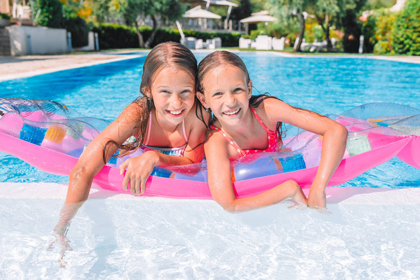 Adorable little sisters play in outdoor swimming pool - Photo, Image
