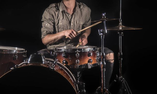 Профессиональный барабанщик, играющий на барабанах на сцене на черном B
 - Фото, изображение