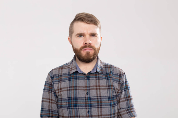 Портрет сомнительного бородатого мужчины в повседневной клетчатой рубашке, смотрящего с нерешительным выражением лица, демонстрирующего сомнения и колебания
. - Фото, изображение