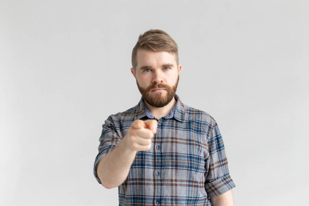 Hombre enojado con barba, con el dedo apuntando hacia la cámara sobre un fondo blanco
 - Foto, Imagen