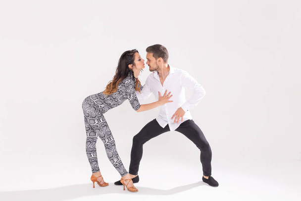 Společenské tance, bachata, kizomba, zouk, pojem tango - muž objetí žena při tanci nad bílým pozadím s kopií prostoru - Fotografie, Obrázek