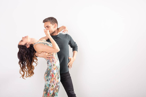 Social dance, bachata, salsa, kizomba, zouk, tango concept - Man hugs woman while dancing over white background with copy space - Zdjęcie, obraz