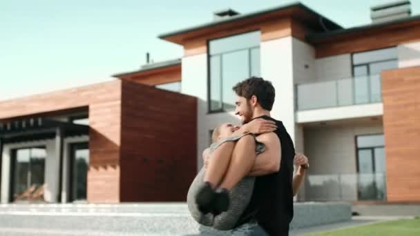 Mladý muž, který drží ženu poblíž luxusního domu. Bohatá rodina v blízkosti nové vily. - Záběry, video