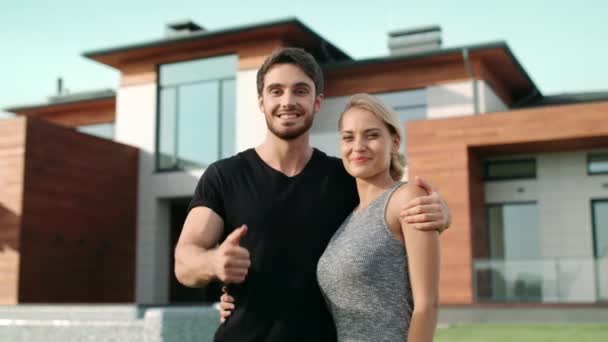 Happy couple making thumbs up gesture near luxury house. - Footage, Video