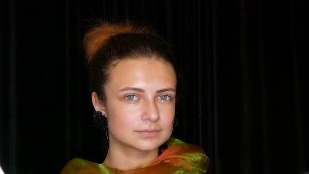Jeune jolie adolescente aux cheveux roux en boucles d'oreilles noires et une écharpe verte pose sans maquillage dans un studio photo modèle
 - Séquence, vidéo